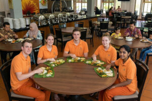 Five students eating on banana leaves in restaurant