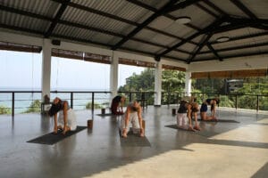 Group practicing yoga in open-air oceanfront studio
