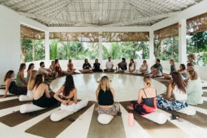 Group meditation circle in open-air tropical pavilion