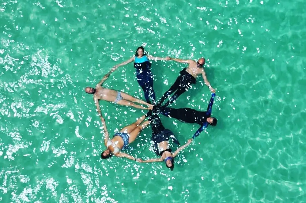 Six people floating in turquoise water holding hands