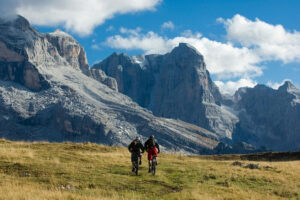 Two cyclists riding near dramatic mountain cliffs