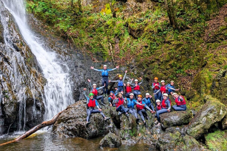 Group posing by waterfall in forest canyon