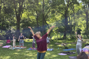 Group practicing yoga in sunny park clearing
