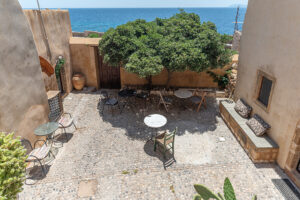 Mediterranean courtyard with tables, tree, and ocean view