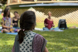 Women practicing outdoor meditation on grassy lawn