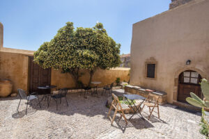 Sunlit cobblestone courtyard with tables and flowering tree