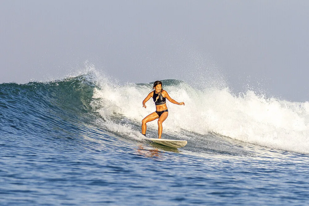 Woman surfing during a Padang Padang Surf Camp session