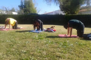 Three people practicing yoga on grassy lawn