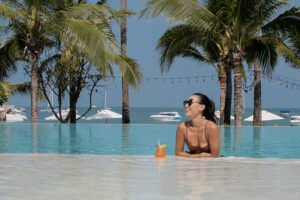Woman relaxing in infinity pool by ocean
