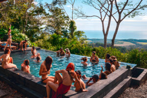 Friends relaxing in infinity pool overlooking ocean