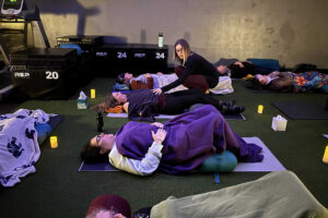 Instructor guiding restorative yoga class with participants lying down