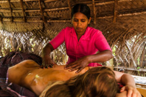 Woman giving oil massage in rustic spa hut