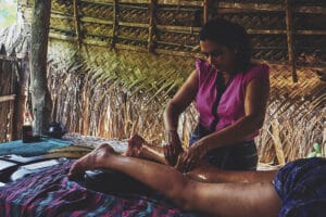 Woman giving leg massage in thatched hut