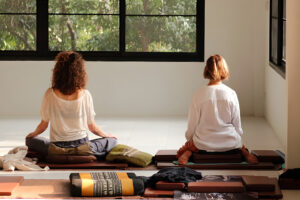 Two women meditating in bright yoga studio