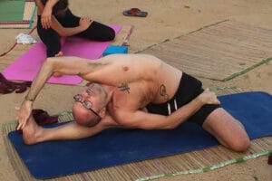 Man performing advanced yoga stretch on mat outdoors