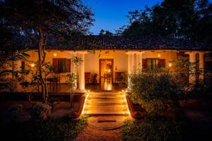 Warmly lit villa entrance at night with garden